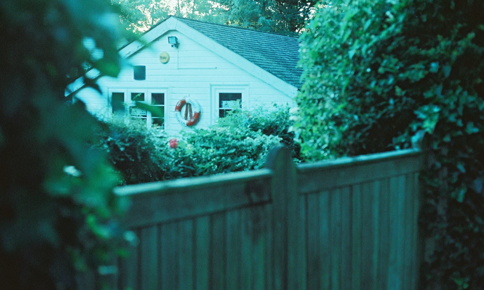 Small white cottage behind a wooden fence